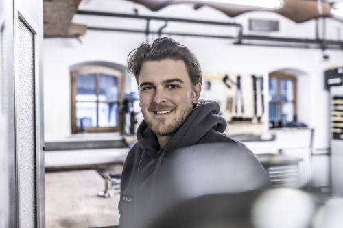 Ein lächelnder Mann in einem Werkraum, der sich auf moderne Klimatechnik spezialisiert hat.