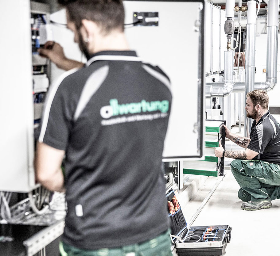 Zwei Techniker in München arbeiten konzentriert an der Lüftungstechnik, während sie ein Klimagerät warten.