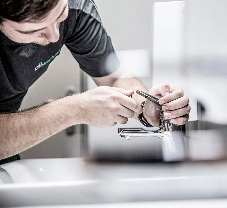 Ein Handwerker in München installiert sorgfältig eine Armatur im Bereich der Sanitärtechnik.